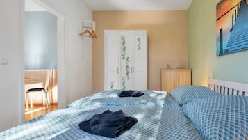 Ein Schlafzimmer mit Bett, Kleiderschrank, Schreibtisch und Stuhl.
