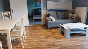 A living room with a sofa, a coffee table, and a dining area with chairs.