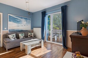 A living room with a sofa, a coffee table, and a painting of birds.