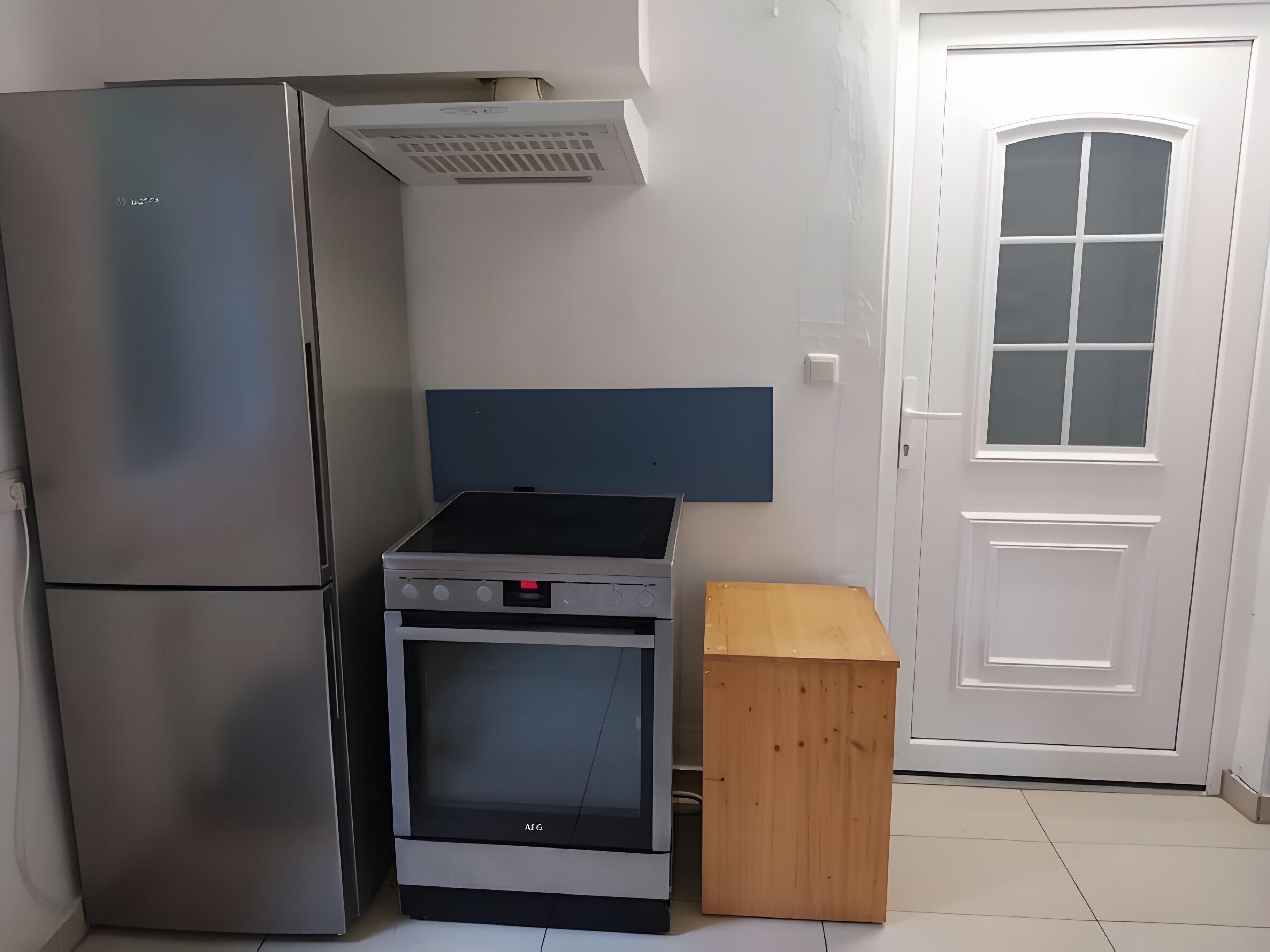 Une cuisine équipée d’un réfrigérateur en acier inoxydable, d’un four encastré et d’un meuble en bois.