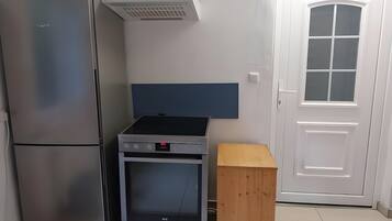 Une cuisine équipée d’un réfrigérateur en acier inoxydable, d’un four encastré et d’un meuble en bois.
