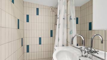 A bathroom with a white sink, chrome faucet, and a shower curtain with a pattern.