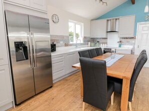 Una cocina moderna con electrodomésticos de acero inoxidable, una mesa de comedor de madera y sillas negras.