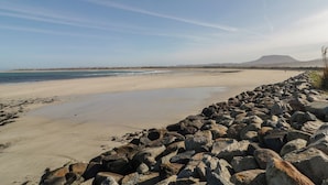 A beach with a rocky shoreline, a clear sky, and distant hills. - Cabin 4 Doire Chonair (Gortahork)
