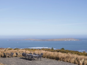Une vue sur la côte, avec un espace aménagé pour s’asseoir et une ligne de rivage visible au loin.
