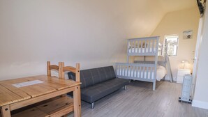 Ein Zimmer mit einem Holztisch, einem grauen Sofa und einem Etagenbett.