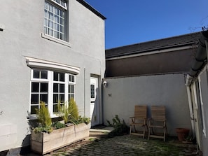 A building with a white exterior, a wooden bench, and a planter with plants. - Witts End, Marske-By-The-Sea (Redcar)