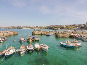 Un porto con numerose imbarcazioni ormeggiate, un cielo sereno e edifici sullo sfondo.