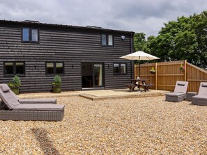 A modern building with a gravel patio, outdoor seating, and a wooden fence. - The Old Dairy, Adiham, near Wingham, Kent. (Canterbury)
