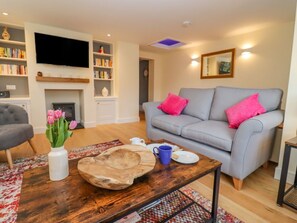 A living room with a grey sofa, a coffee table, a fireplace, and a bookshelf. - Holly Cottage, Stratford-Upon-Avon (Stratford-upon-Avon)