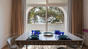 A dining table set with plates, glasses, and cutlery, with a view of trees through a window. - Villa Luna Rossa, Capri (Capri)