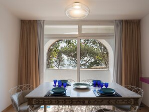 A dining table set with plates, glasses, and cutlery, with a view of trees through a window. - Villa Luna Rossa, Capri (Capri)