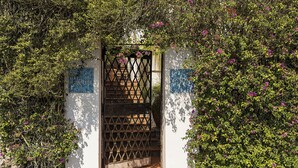 A white building with a metal gate, surrounded by greenery and flowers. - Villa Luna Rossa, Capri (Capri)