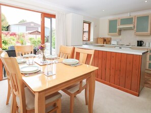 Ein Essbereich mit Holztisch und -stühlen, eine Küche mit Holzausstattung und Blick auf den Garten.