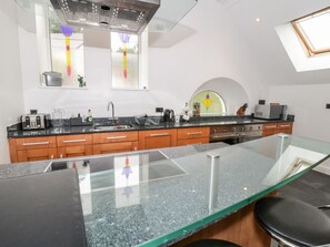 Una cocina moderna con encimera de granito, electrodomésticos de acero inoxidable, armarios de madera y un tragaluz.