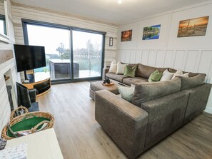 A living room with a sofa, a flat-screen TV, a sliding glass door, and a view of the outdoors.