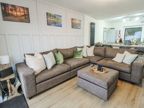 A living room with a sectional sofa, a coffee table, and artwork on the walls.