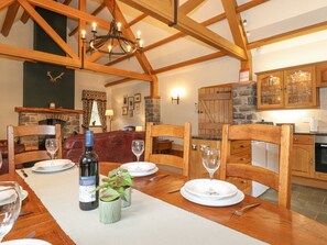 A dining area with a wooden table set for four, a bottle of wine, and a vase with flowers. - Glen View Dunscore nr Dumfries (Dumfries)