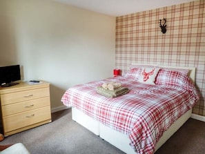 Une chambre à coucher comprenant un lit, une commode et un téléviseur fixé au mur.