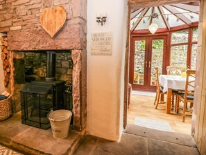 A stone fireplace with a heart-shaped decoration, a sign with motivational text, and a wooden table set for dining in a bright room. - The Lodge, Greystoke (Penrith)