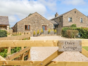 Ein Steinhäuschen mit einem hölzernen Tor, auf dem 'Dairy Cottage' steht.