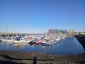 A marina with multiple boats docked, a clear sky, and buildings in the background. - Victoria Cottage, Amble (Amble)