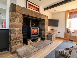 A stone fireplace with a television, a bookshelf, and a window with a view.