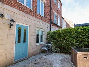 A residential building with a blue door, a small outdoor seating area, and a hedge. - The Shipwrights, Whitby (Whitby)
