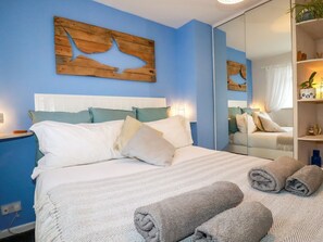 A bedroom with a bed, pillows, a mirror, and a shelf with items. - Estuary View, Newquay (Newquay)