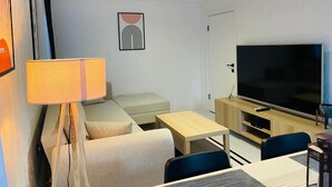 Ett modernt vardagsrum med en soffa, en tv, en lampa och ett litet bord.