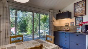 Eine Küche mit großem Fenster, einem Tisch mit Patchworkdecke und Schränken.