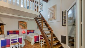 Ein Zimmer mit zwei Betten, einer Holztreppe und einem großen Fenster.