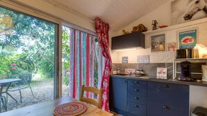 Eine Küche mit einem Holztisch, einem blauen Schrank und einem Fenster mit Blick auf Grünflächen.