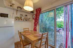 Un coin repas avec une table en bois, des chaises et un réfrigérateur.