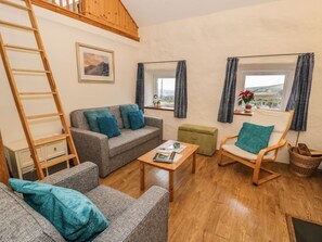 A cozy living room with a sofa, armchair, wooden coffee table, and a ladder against the wall. - Charming Y Bwthyn Retreat in Llanberis (Caernarfon)