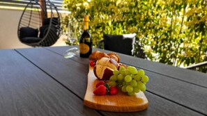 A wooden table with a fruit and cheese board, a bottle, and a hanging chair. - Modern vacation apartment with a large terrace and private parking (Crikvenica)