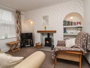 Ein gemütliches Wohnzimmer mit Kamin, Fernseher, Bücherregal und bequemen Sesseln.