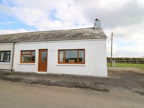 A single-story white building with a sloped roof, a wooden door, and two windows with wooden frames.
