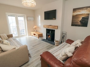 A living room with a fireplace, a sofa, a television, and a painting. - 11 Castle Gardens, Scarborough (Scarborough)