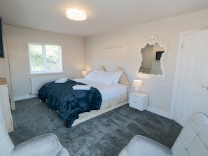 A bedroom with a bed, bedside tables, a mirror, a window, and a door. - 11 Castle Gardens, Scarborough (Scarborough)