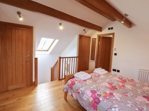 A bedroom with a wooden bed, a skylight, a staircase, and wooden doors. - Mallard Cottage, Whitby (Whitby)