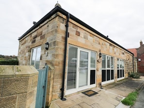 A stone building with a flat roof, large windows, and a visible door. - Mallard Cottage, Whitby (Whitby)