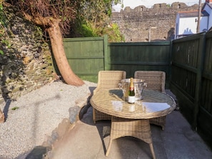 A wicker table with two chairs, a bottle of champagne, and a glass. - 6 Uppergate Street Rose Cottage, Conwy (Conwy)