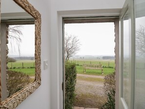Ein Durchgang mit Blick auf ein grünes Feld, eine Bank und einen Zaun.