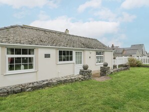 A two-story building with a stone facade, white windows, and a stone pathway leading to the entrance. - Halcyon Annexe, Benllech (Moelfre)