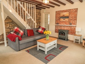 A living room with a grey sofa, a wooden coffee table, a fireplace, and a staircase.