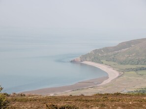 A coastal landscape with a curved shoreline, grassy hills, and a clear view of the sea. - The Old Thatch, Porlock. 1bed. (Minehead)