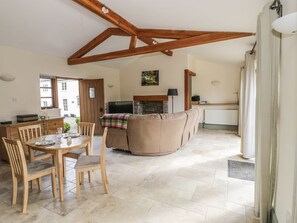 A spacious living area with a wooden ceiling, a fireplace, a sofa, and a dining table with chairs. - The Old Dairy, Newnham-On-Severn (Newnham)