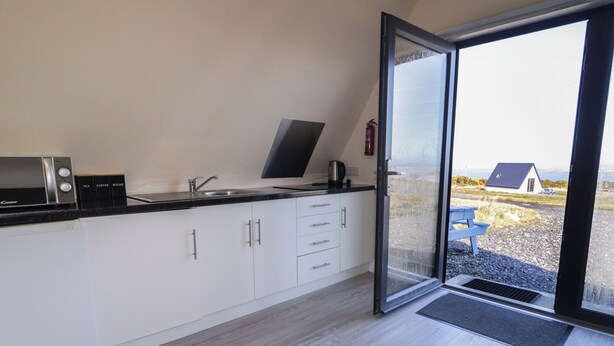 A modern kitchen with a built-in microwave, coffee maker, and sugar dispenser. - Cabin 9 Inis Beag (Gortahork)