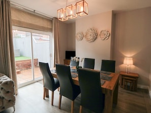 Een eetruimte met een houten tafel, zwarte stoelen en een kroonluchter.